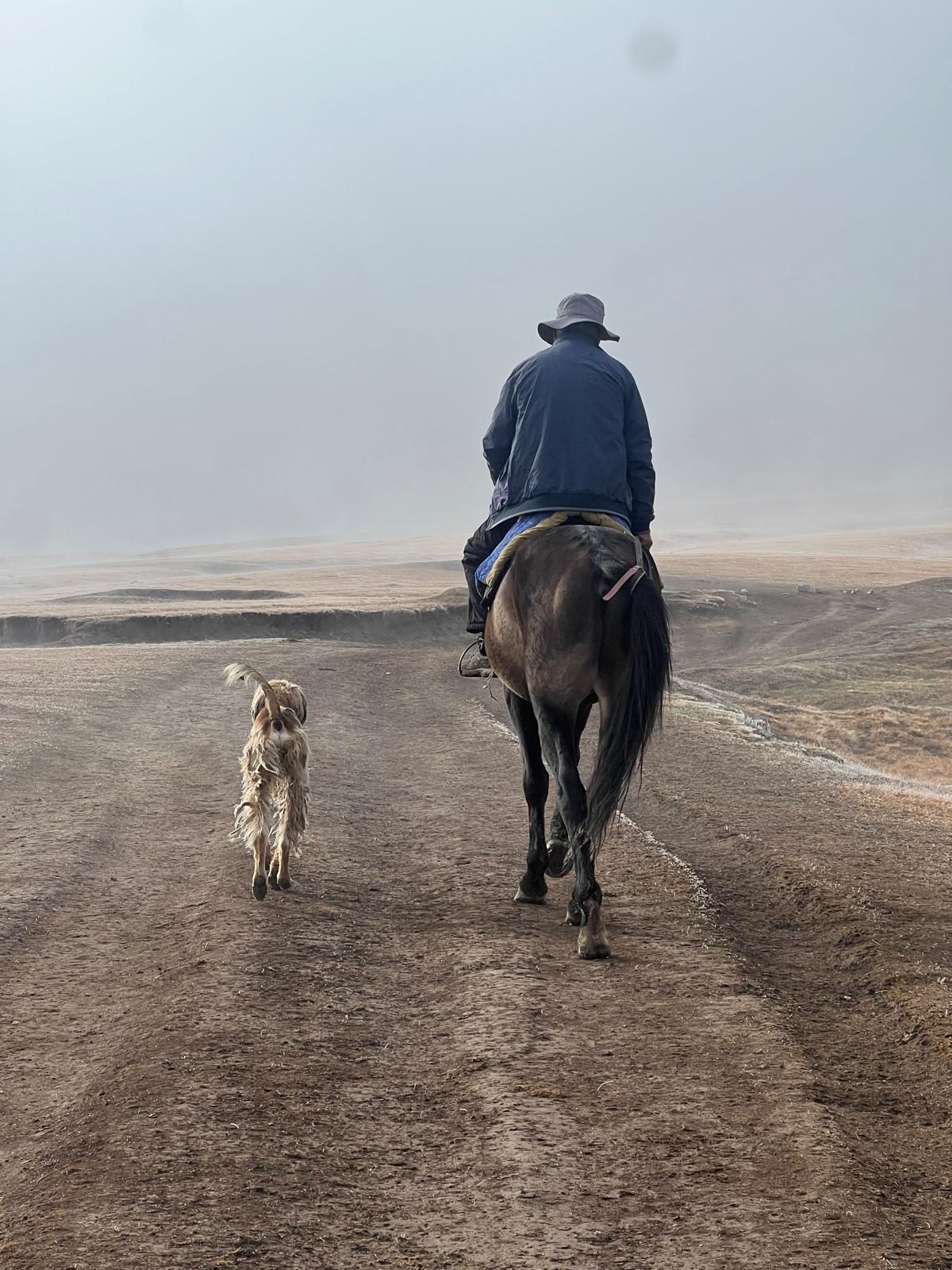 The father riding along a dirt road with a dog