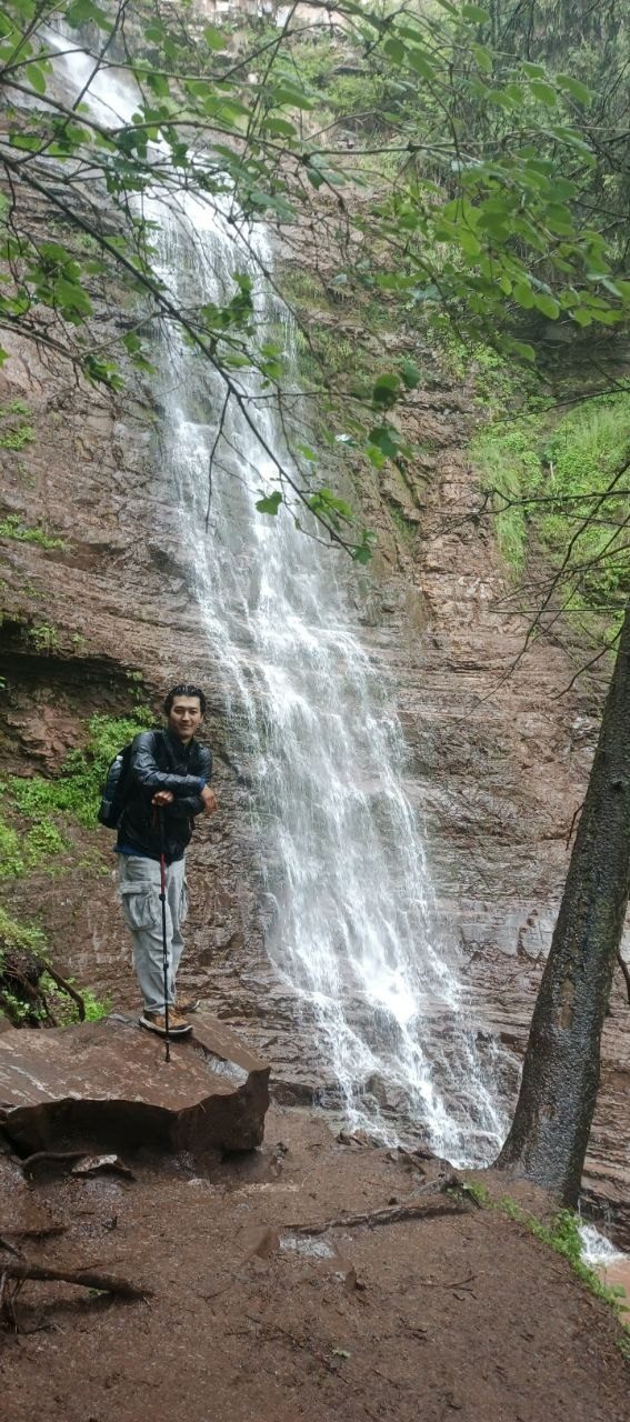 A tall waterfall on a forested mountain path